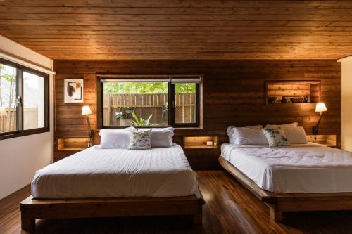 two beds in a room with wooden walls at Shan Xing Ji Ye Homestay in Nanzhuang