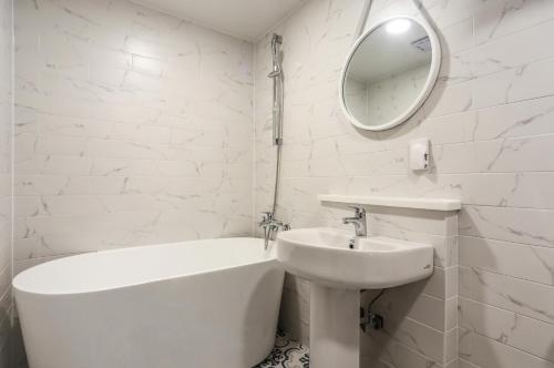 a white bathroom with a sink and a tub and a mirror at 엘루이호텔 in Busan