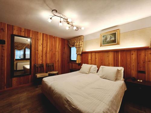 a bedroom with a large bed with wooden walls at Hotel L' Aiglon in Champoluc