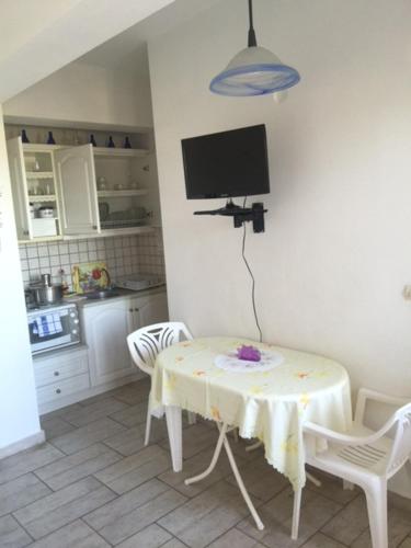 a kitchen with a table and a tv on the wall at AVRA Apartments & Studios in Frý