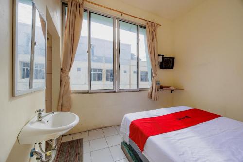 a bedroom with a bed and a sink and a window at RedDoorz near Soekarno Hatta Airport 3 in Tangerang