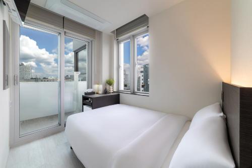 a white bedroom with a bed and a large window at HiMate Dongdaemun in Seoul