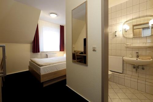 a bathroom with a bed and a sink and a mirror at Hotel Stadt Kamen in Kamen