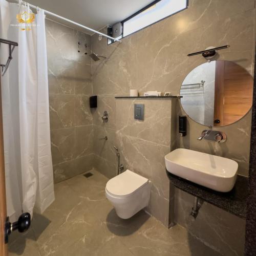 a bathroom with a toilet and a sink and a mirror at Prakruthi Retreat Belagavi in Belgaum