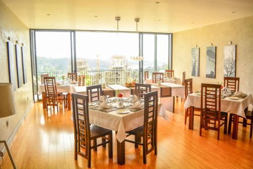 a dining room with tables and chairs and large windows at Highland Stonehouse in Nuwara Eliya