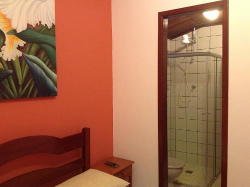 a bathroom with a toilet and a painting on the wall at Pousada Telhado Azul in Abraão
