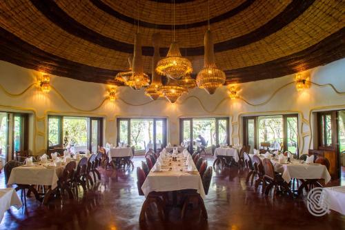 a dining room with white tables and chairs and chandeliers at Lake Manyara Serena Safari Lodge in Karatu