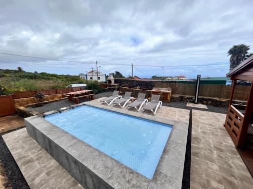 a swimming pool with two chairs and a table at Betenama - Rustic Hideaway with Pool & Garden in Tesbabo