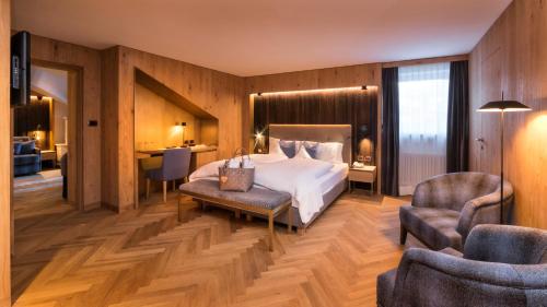 a bedroom with a bed and a chair and a desk at Hotel Genziana in Ortisei