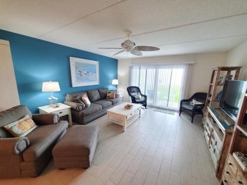 a living room with a couch and a tv at Summerhouse 104- Direct Oceanfront condo in St. Augustine