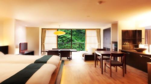 a hotel room with a bed and a dining room at Aizu Higashiyama Onsen "Shosuke no Yado Takinoyu" since1880 in Aizuwakamatsu