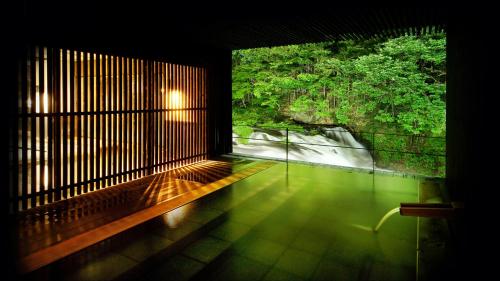 a room with a window with a view of a forest at Aizu Higashiyama Onsen "Shosuke no Yado Takinoyu" since1880 in Aizuwakamatsu