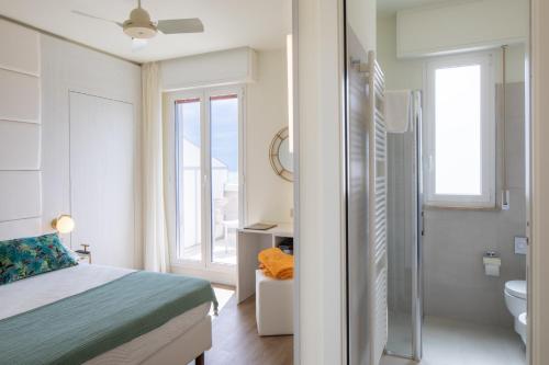 a bedroom with a bed and a bathroom with a toilet at UNA HOTELS Imperial Beach Hotel in Marotta