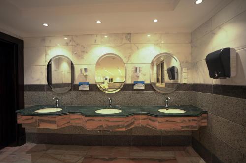 a bathroom with three sinks and three mirrors at فندق ام جي كراون 3 - MG Crown Hotel 3 in Medina