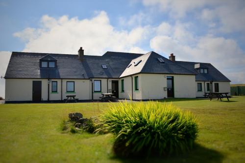 a white house sitting in a grassy field at Decca - Self Catering Shetland in Lerwick
