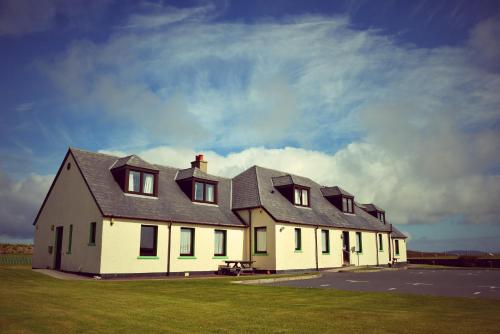 a white house sitting in front of a house on a sunny day at Decca - Self Catering Shetland in Lerwick