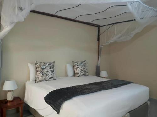 a white bed with a canopy in a bedroom at 1688 BB7 Suites in Victoria Falls