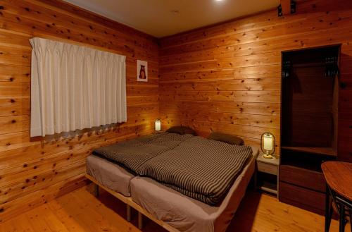 a bedroom with a bed in a room with wooden walls at Azumino Bear's Inn in Azumino