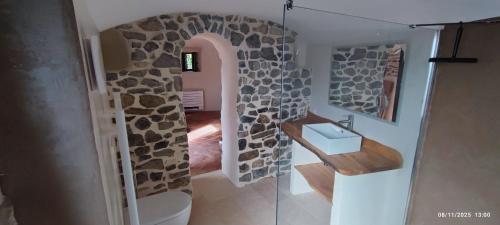 a bathroom with a stone wall with a toilet and a sink at MAS Estrela Chambre Lo Nis in Bessèges