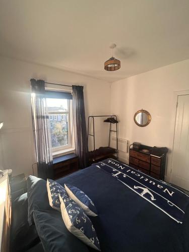 a bedroom with a bed with a blue comforter and a window at 'Nautical Nook' -Island Escape in Millport