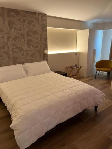 a bedroom with a large white bed and a chair at Masseria Brigarè in Cassano delle Murge