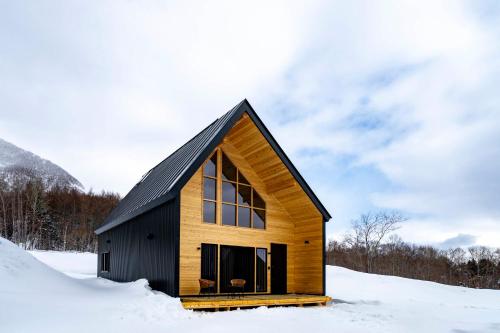 a wooden house with a black roof in the snow at Rusutsu Hills Northern Ridge in Rusutsu