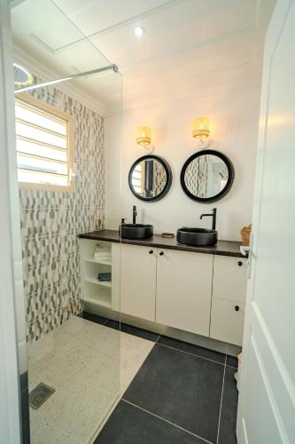 a bathroom with two sinks and two mirrors at La Villa Bleue, Pieds dans l'eau in Saint-Leu