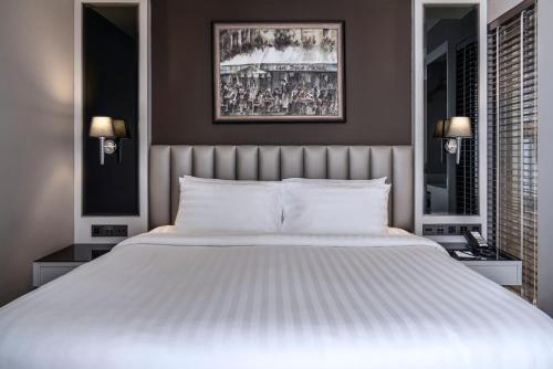 a large white bed in a bedroom with two lamps at Quartier by Montraj Sukhumvit Bangkok in Bangkok