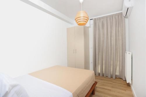 a white bedroom with a bed and a window at Samà Housing in Larisa
