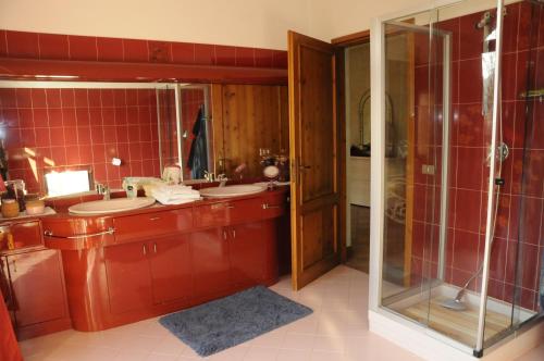 a bathroom with two sinks and a glass shower at Cascina tra le vecchie vigne con piscina in Canale