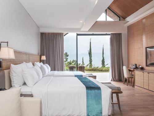 a bedroom with a large bed and a large window at Marianna Resort And Convention Tuktuk - Samosir, Marclan Collection in Tuktuk Siadong