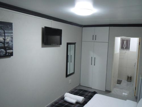 a bedroom with a bed and a tv on the wall at Daeka Guesthouse in Kempton Park