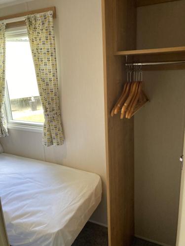 a small bedroom with a bed and a window at 3 Bedroom, 8 berth Luxury caravan in Belton