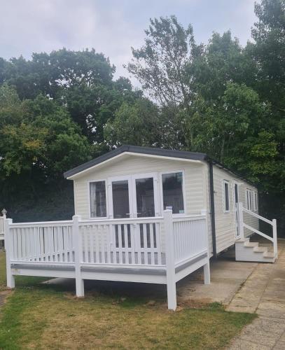 a small white house with a porch and a porch at 3 Bedroom, 8 berth Luxury caravan in Belton