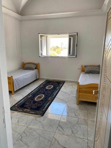 a room with two beds and a rug and a window at Maison a midoun in Midoun