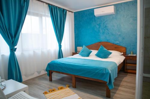 a bedroom with a bed with blue walls and blue curtains at Casa din Delta in Murighiol