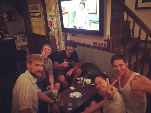 a group of people sitting around a table in a room at IZA Kamakura Guest House and Bar in Kamakura