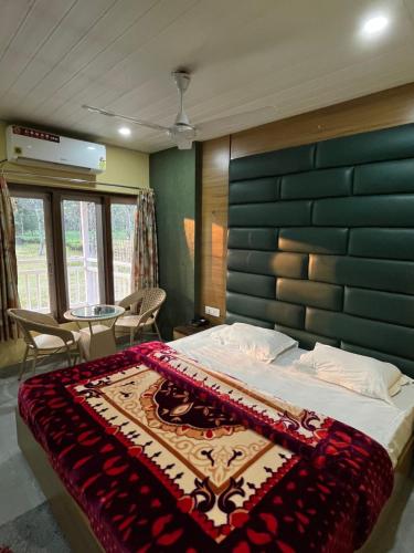 a bedroom with a large bed with a blue headboard at Gorumara Jungle Resort in Chālsa