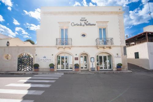 a large white building with windows on a street at Corte Di Nettuno - CDSHotels in Otranto