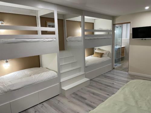 a room with white bunk beds and a television at Les bulles lissoises in Lisse