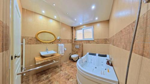 a bathroom with a tub and a sink and a mirror at Бутиков хотел History in Haskovo