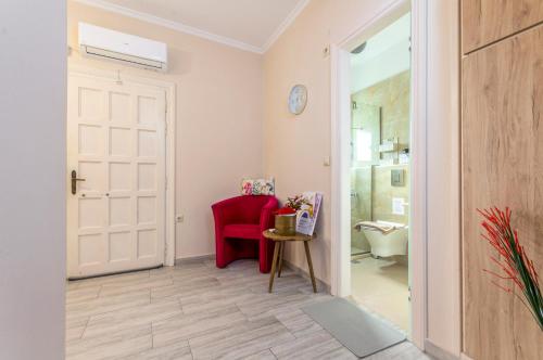 a hallway with a red chair and a bathroom at Potamos Apartments in Sidari