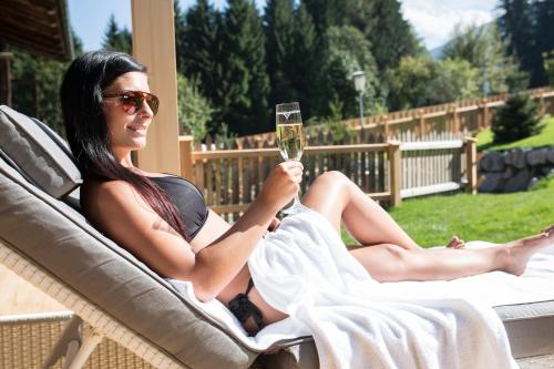 a woman sitting in a chair holding a glass of wine at Bergchalet Rauchenhof in Reith im Alpbachtal