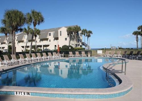 a large swimming pool with chairs and a building at Summerhouse 147 condo in St. Augustine