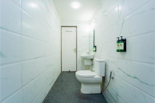 a white bathroom with a toilet and a sink at HHW Hotel- Agra in Agra