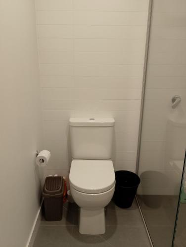 a white bathroom with a toilet and a shower at Cozy 1 Bedroom Apt Parkside Pool Gym Parking close CBD in Melbourne