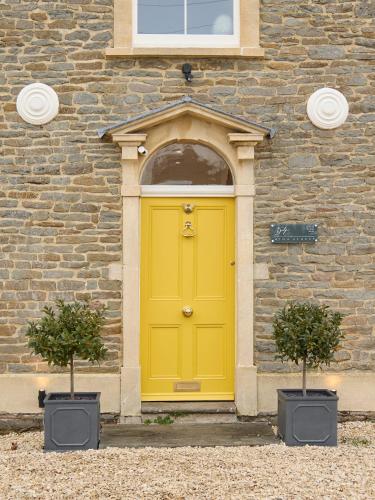 a yellow door on a brick building with two plants at The Old School House in Bristol