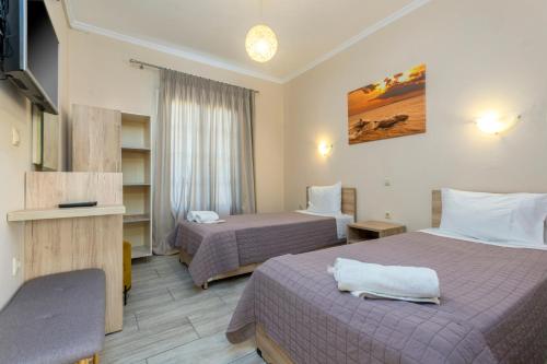 a hotel room with two beds and a television at Potamos Apartments in Sidari