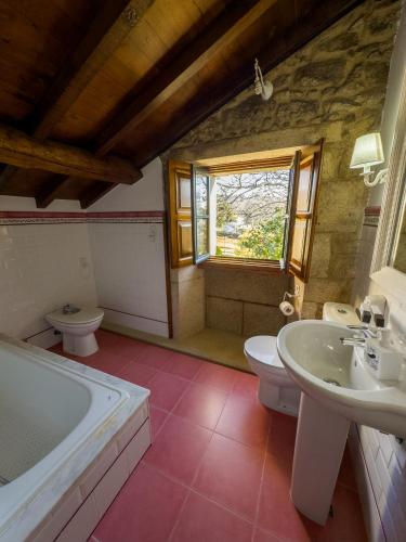 a bathroom with two sinks and a tub and a toilet at Hotel Vila As Pedras in Roxos