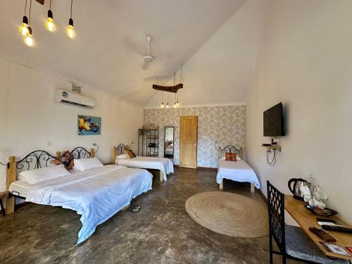 a bedroom with two beds and a table and a tv at Boulevard Inn Mt Meru in Arusha